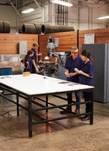 engineers-working-on-machines-in-busy-metal-worksh-2024-10-20-10-43-39-utc